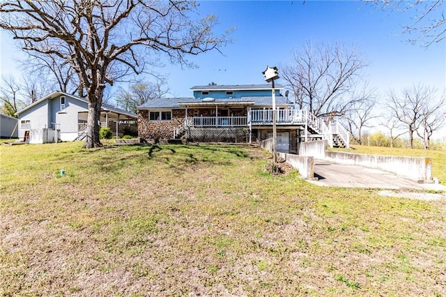 rear view of house featuring an attached garage, covered porch, a lawn, stairway, and concrete driveway