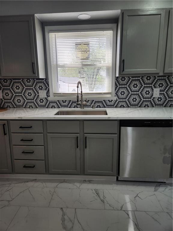 kitchen featuring gray cabinets, stainless steel dishwasher, a sink, and marble finish floor