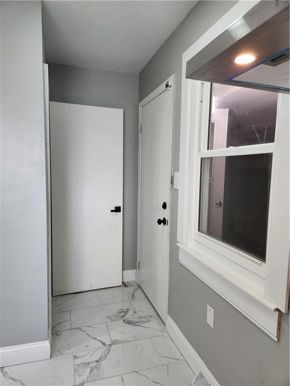 hall featuring marble finish floor and baseboards