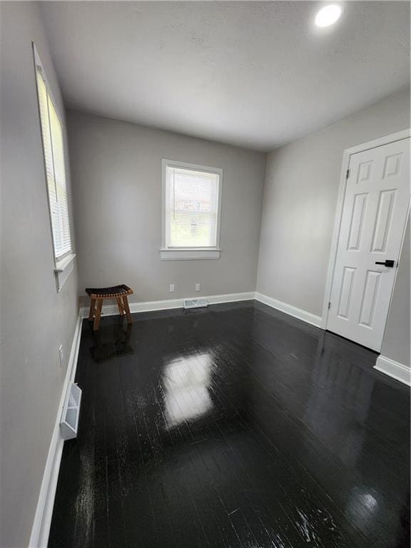 spare room featuring recessed lighting, dark wood-style flooring, baseboards, and visible vents