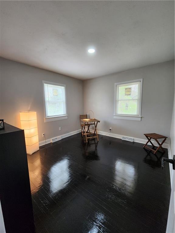 interior space featuring wood-type flooring, baseboards, recessed lighting, and visible vents