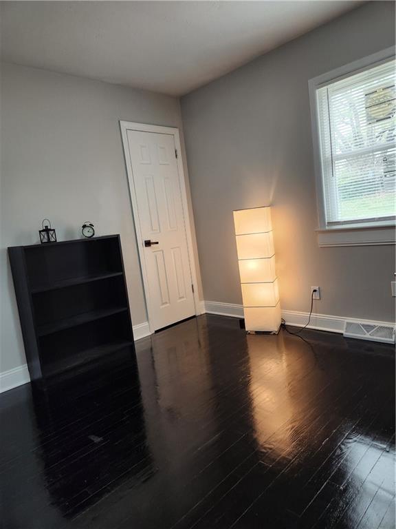 spare room with wood-type flooring and baseboards