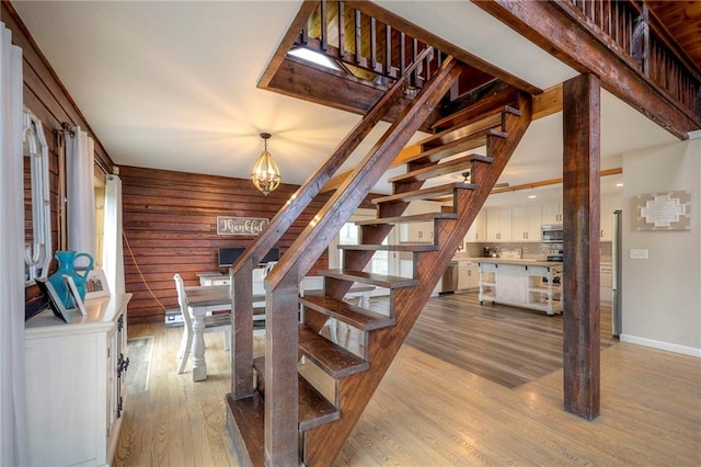 43 901st Rd, Clinton, MO 64735 - staircase featuring wood walls, baseboards, a notable chandelier, and wood finished floors