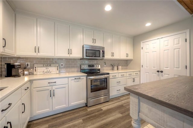 43 901st Rd, Clinton, MO 64735 - kitchen with white cabinets, recessed lighting, wood finished floors, stainless steel appliances, and decorative backsplash