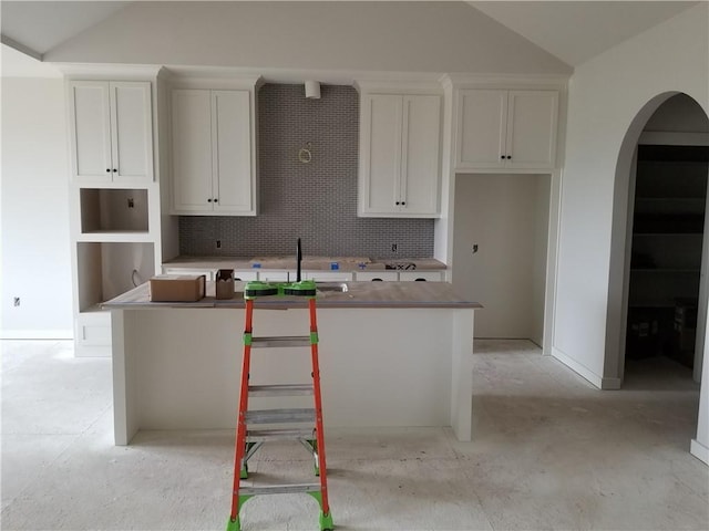 4967 146th St, Basehor, KS 66007 - kitchen with a kitchen island with sink, arched walkways, backsplash, white cabinets, and lofted ceiling