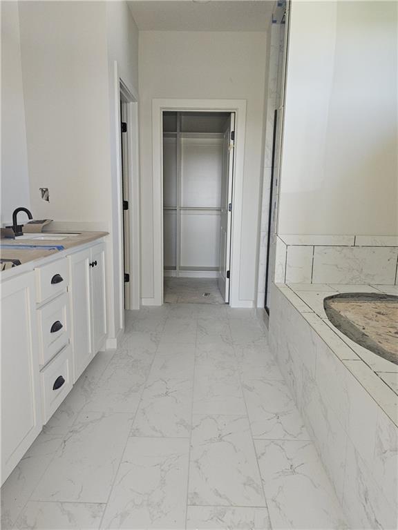 4967 146th St, Basehor, KS 66007 - full bath featuring marble look tiles, a tub, a sink, and a closet