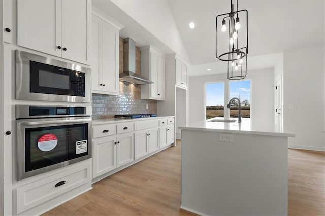 4967 146th St, Basehor, KS 66007 - kitchen with appliances with stainless steel finishes, a sink, wall chimney exhaust hood, white cabinetry, and decorative backsplash
