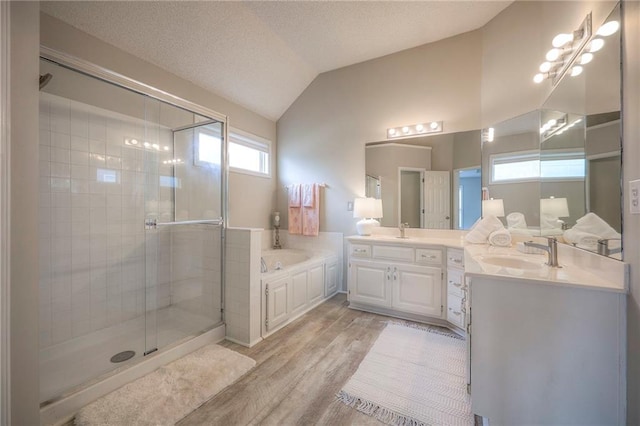 bathroom featuring wood finished floors, a stall shower, a bath, lofted ceiling, and vanity