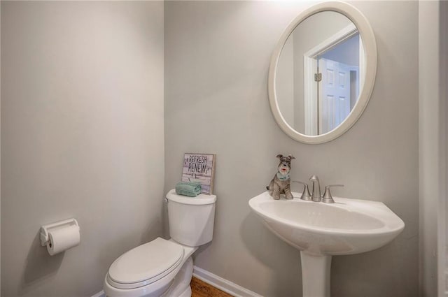 half bathroom featuring toilet and baseboards