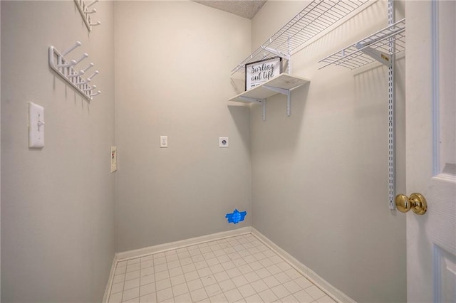 laundry area featuring electric dryer hookup, baseboards, and tile patterned flooring
