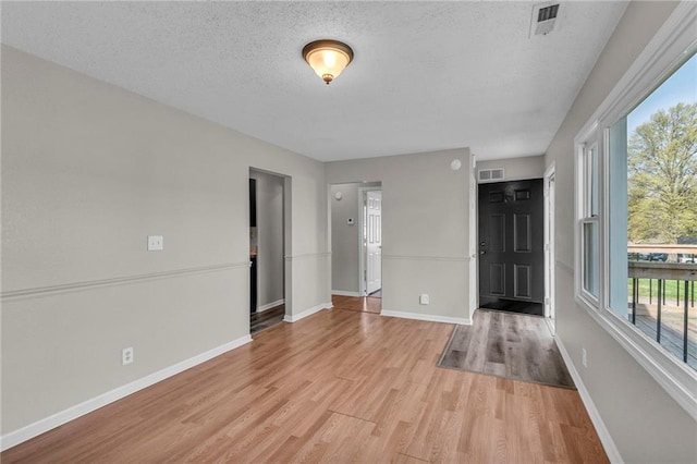 2411 NE 60th St, Gladstone, MO 64118 - unfurnished room with baseboards, light wood-style flooring, visible vents, and a textured ceiling