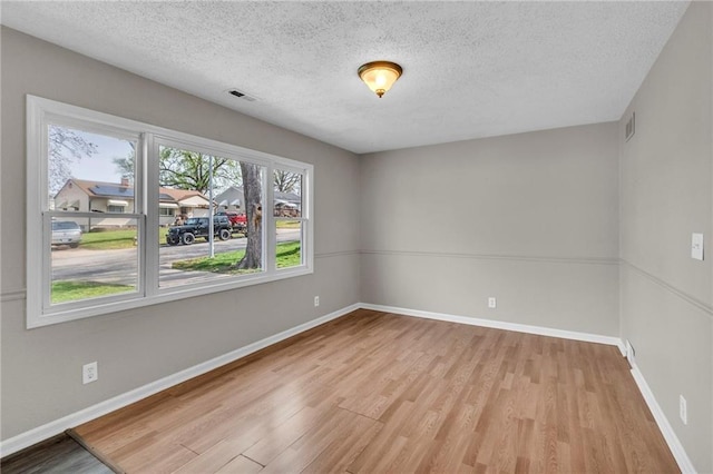 2411 NE 60th St, Gladstone, MO 64118 - unfurnished room with visible vents, baseboards, wood finished floors, and a textured ceiling