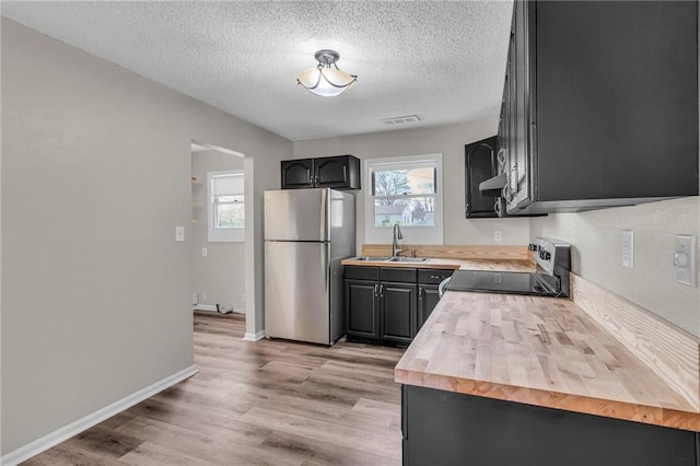 2411 NE 60th St, Gladstone, MO 64118 - kitchen with a sink, a textured ceiling, visible vents, freestanding refrigerator, and electric range oven