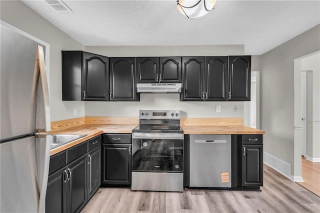 2411 NE 60th St, Gladstone, MO 64118 - kitchen with dark cabinets, under cabinet range hood, and appliances with stainless steel finishes
