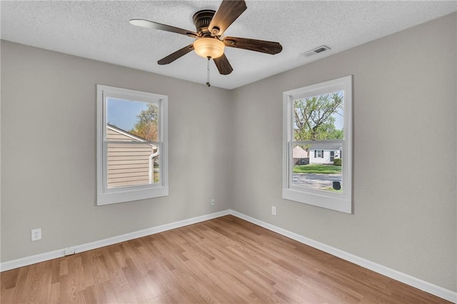 2411 NE 60th St, Gladstone, MO 64118 - empty room with a textured ceiling, wood finished floors, visible vents, and a healthy amount of sunlight
