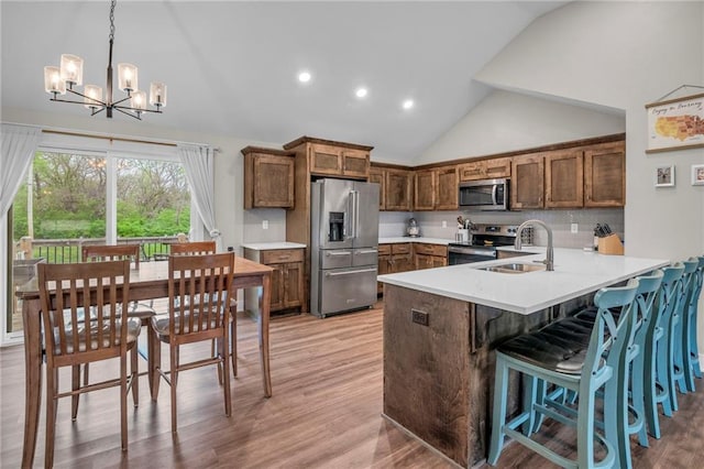 12631 Fountain Lake Cir, Grandview, MO 64030 - kitchen featuring stainless steel appliances, a chandelier, a peninsula, light countertops, and light wood finished floors