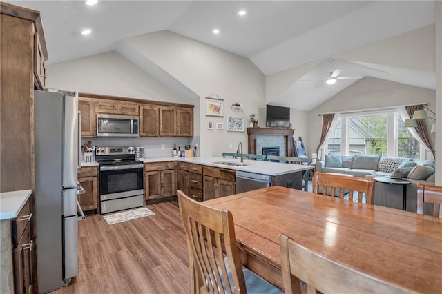 12631 Fountain Lake Cir, Grandview, MO 64030 - kitchen featuring appliances with stainless steel finishes, vaulted ceiling, open floor plan, a ceiling fan, and light wood-style floors