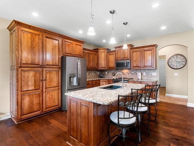 105 Fox Den Ct, Savannah, MO 64485 - kitchen featuring baseboards, light stone counters, backsplash, brown cabinetry, and appliances with stainless steel finishes
