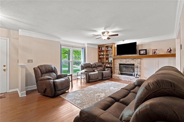 living room with wood finished floors, a fireplace, baseboards, a textured ceiling, and a ceiling fan