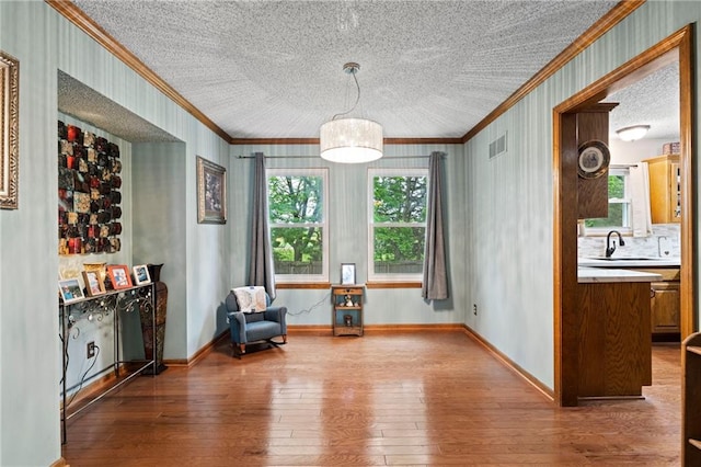 sitting room with crown molding, a wealth of natural light, and hardwood / wood-style floors