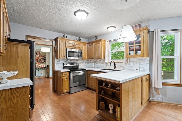kitchen featuring backsplash, stainless steel appliances, a sink, and light wood-type flooring