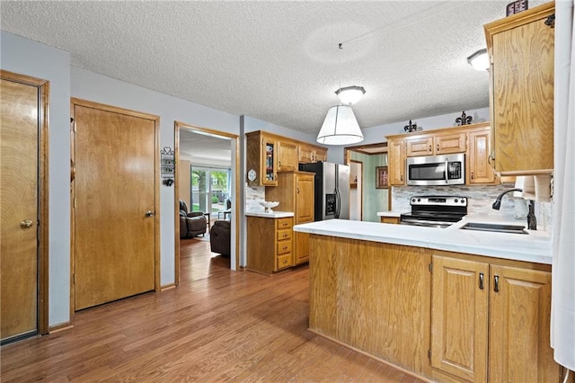 kitchen with light wood-type flooring, a sink, light countertops, and stainless steel appliances