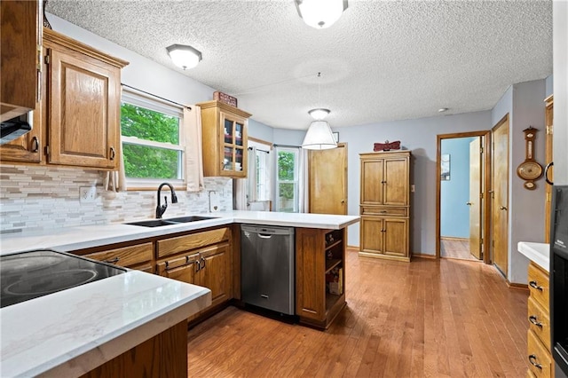 kitchen featuring a sink, hardwood / wood-style floors, a peninsula, tasteful backsplash, and stainless steel dishwasher