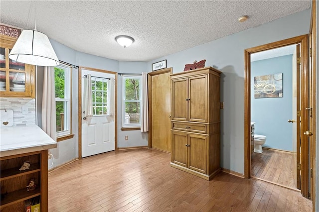 doorway to outside featuring light wood-style floors, baseboards, and a textured ceiling