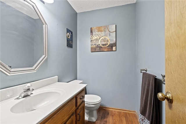 bathroom with vanity, a textured ceiling, wood finished floors, and toilet