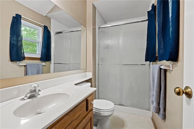 bathroom featuring vanity, toilet, a textured ceiling, and a stall shower