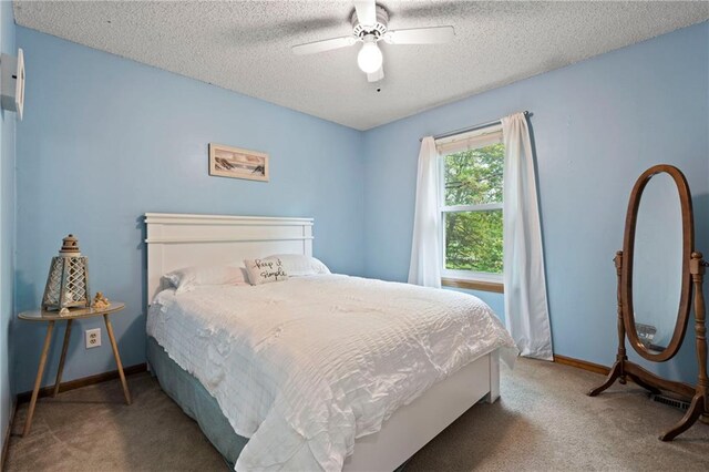 bedroom with baseboards, ceiling fan, carpet, and a textured ceiling