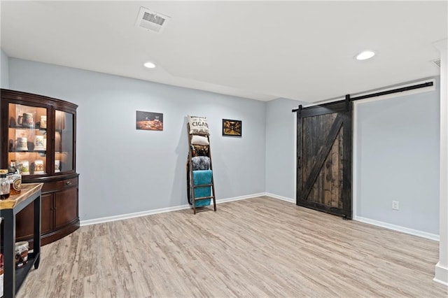 interior space featuring recessed lighting, visible vents, a barn door, and light wood finished floors