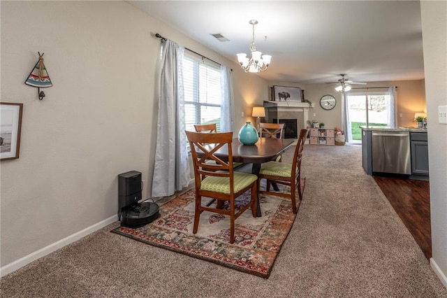 dining space featuring dark carpet, baseboards, visible vents, and ceiling fan with notable chandelier