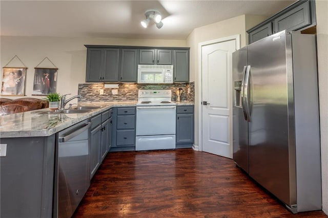 kitchen featuring a peninsula, dark wood finished floors, backsplash, gray cabinetry, and appliances with stainless steel finishes