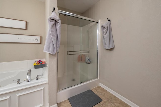 bathroom featuring a garden tub, baseboards, tile patterned flooring, and a stall shower
