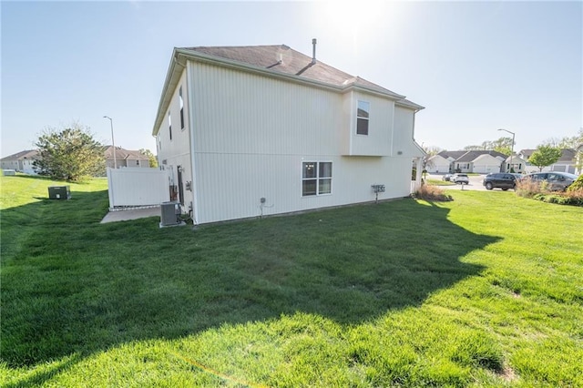 back of property featuring a lawn and central AC