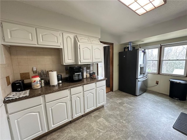83 Grandview Dr, Warrensburg, MO 64093 - kitchen with stainless steel refrigerator with ice dispenser, dark countertops, tasteful backsplash, and white cabinetry
