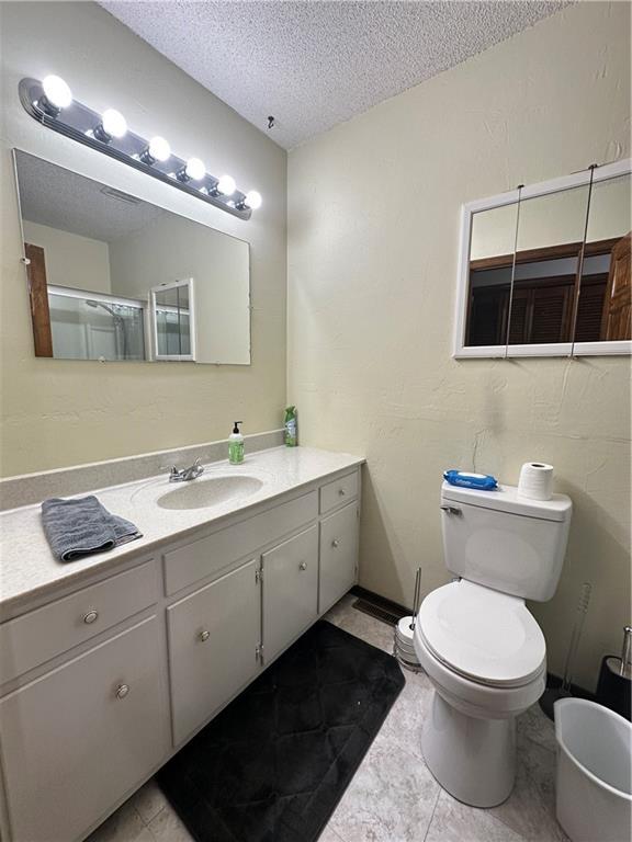 83 Grandview Dr, Warrensburg, MO 64093 - bathroom with a textured ceiling, toilet, vanity, and tile patterned floors