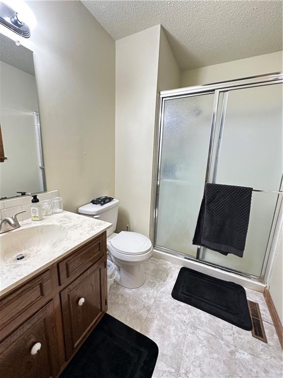 83 Grandview Dr, Warrensburg, MO 64093 - full bath with a stall shower, toilet, vanity, and a textured ceiling