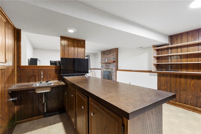 83 Grandview Dr, Warrensburg, MO 64093 - kitchen with a peninsula, dark countertops, a fireplace, light colored carpet, and wood walls