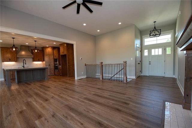 foyer entrance with dark wood-style flooring, baseboards, ceiling fan with notable chandelier, and recessed lighting