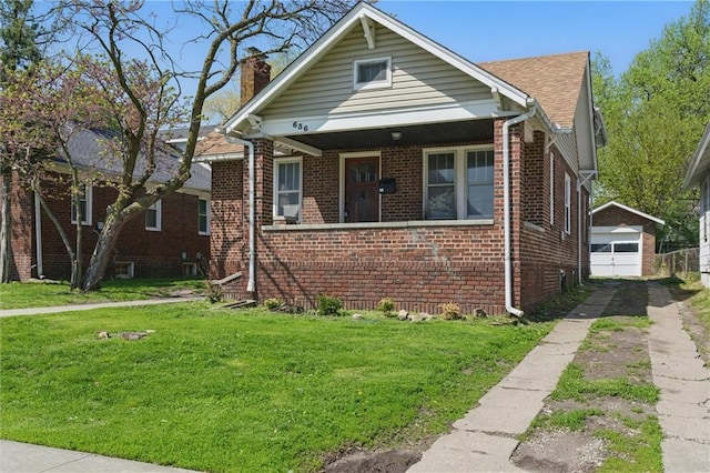 bungalow-style home with concrete driveway, a front lawn, a chimney, a garage, and brick siding