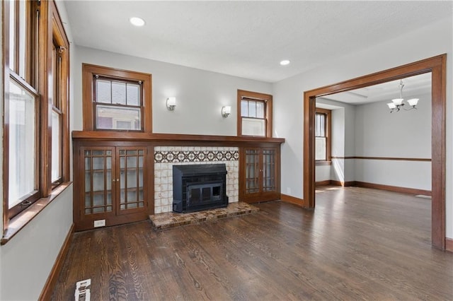 unfurnished living room with a glass covered fireplace, wood finished floors, baseboards, and plenty of natural light