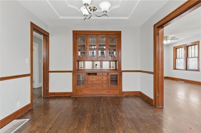 spare room featuring a chandelier, wood finished floors, visible vents, and baseboards