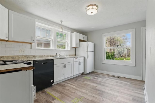 kitchen featuring decorative backsplash, dishwasher, light wood-style flooring, visible vents, and freestanding refrigerator