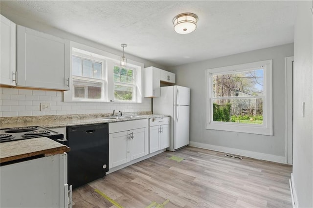 kitchen featuring dishwasher, visible vents, a sink, freestanding refrigerator, and tasteful backsplash