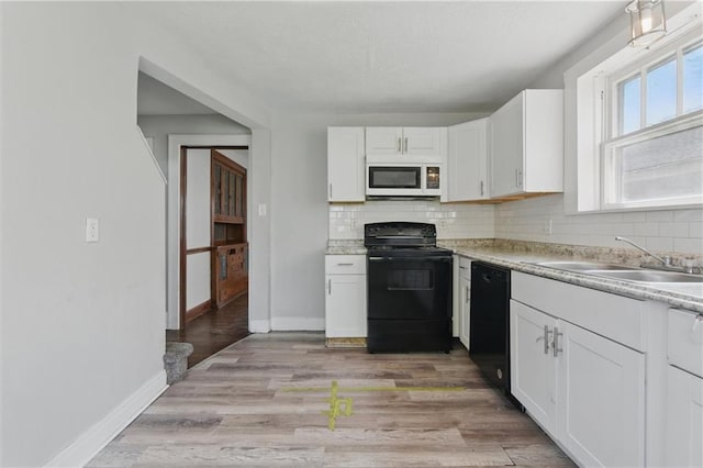 kitchen with backsplash, light countertops, a sink, and black appliances