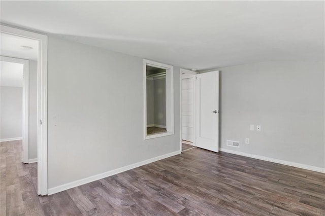 empty room featuring wood finished floors, visible vents, and baseboards