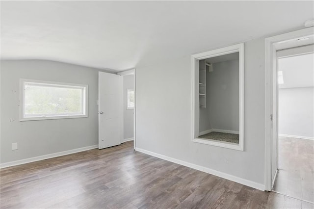 unfurnished room featuring vaulted ceiling, baseboards, and wood finished floors