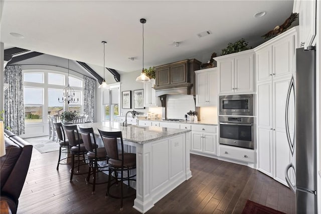 6840 Belmont Dr, Shawnee, KS 66226 - kitchen featuring white cabinets, light stone counters, a center island with sink, appliances with stainless steel finishes, and dark wood-style flooring